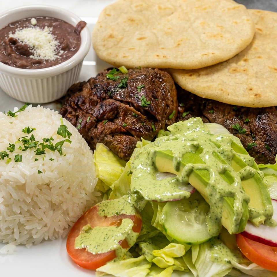 A platter with grilled beef, white rice, black beans, golden corn cakes, and avocado salad drizzled with green sauce.
